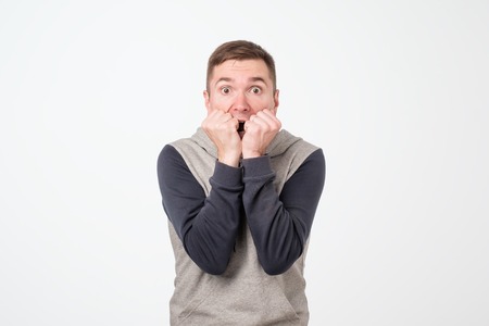 European man covering his mouth with both hands, looking shocked. Surprised, embarrassed and...