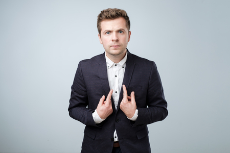 Young european man in suit pointing at himself, making excuses or verbally defending, having perplexed and puzzled look.の写真素材