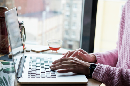Woman is typing on a laptop sitting in coffee shop.の写真素材