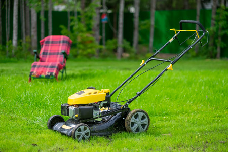 Lawn care concept. Mower standing on green grass on yard.の写真素材