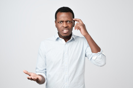 Young european man in white shirt dissatisfied frowns and looks sullenly.の写真素材