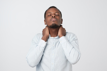 I need a massage. Frustrated african man holding hand on his neckの写真素材