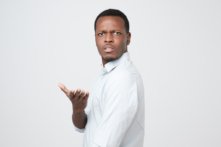 Young african american man in white shirt dissatisfied frowns and looks sullenly.の写真素材