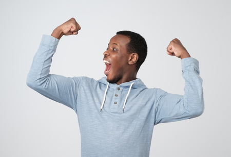 Happy successful african man winning, fists pumped celebrating successの写真素材