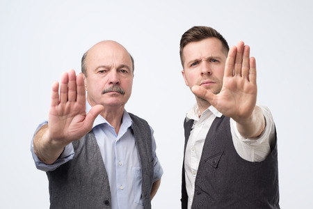 Two mature men giving showing stopt hands gestureの写真素材