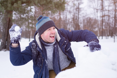 European mature man in warm clothes playing with snow outdoor. Having fun on winter vacation.の写真素材
