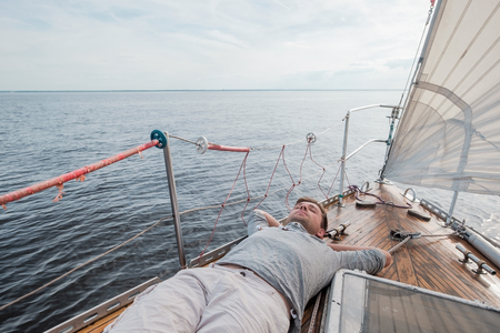 young european man resting on yacht looking at skyの写真素材