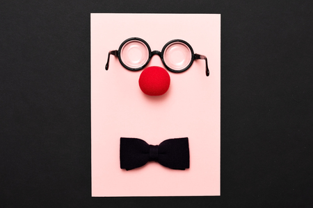 Funny glasses, a red clown nose and tie on a colored background, like a face. Flat lay. Funny costume for the holidays. Anonymous concept.の写真素材