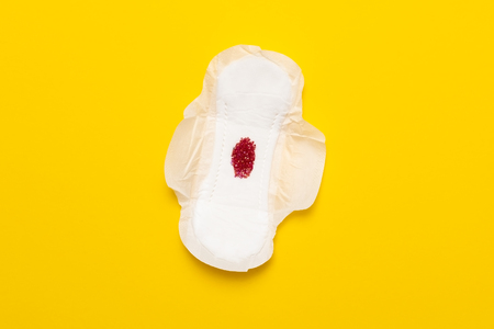 Menstruation period concept. Red drop from beads on pad on yellow backgroundの写真素材