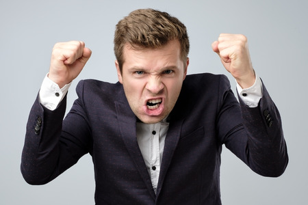 Anger crazy handsome man in suit standing shouting or screaming. indoor studio shot.の写真素材