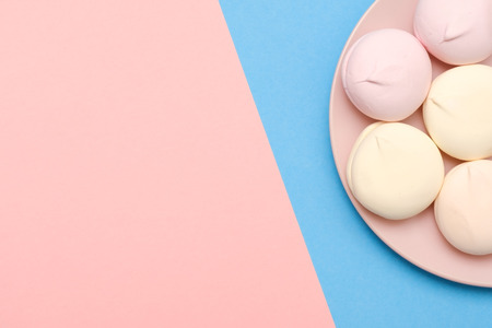 Marshmallows on plate on blue background with copyspace. Flat lay or top view.の写真素材