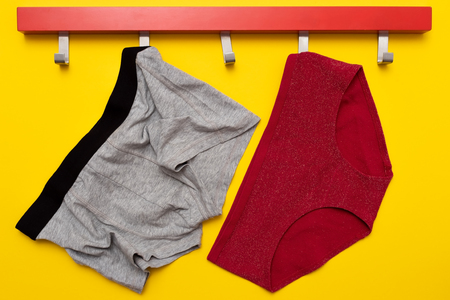 Woman and man pants on red hanger isolated on yellow backgroundの写真素材