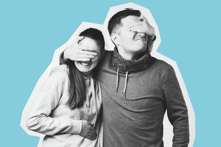 Portrait of a happy young couple, man and woman covering eyes of each other.