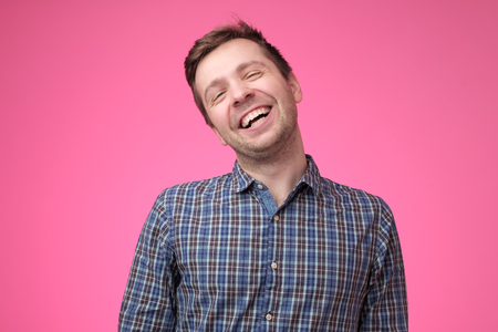 Handsome young man laughing on pink backgroundの写真素材