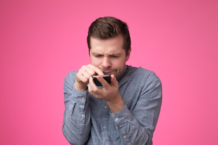 young man standing, using smartphone and watching video with amazed face.の写真素材