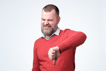 Man in red sweater gives vthumbs down gesture.