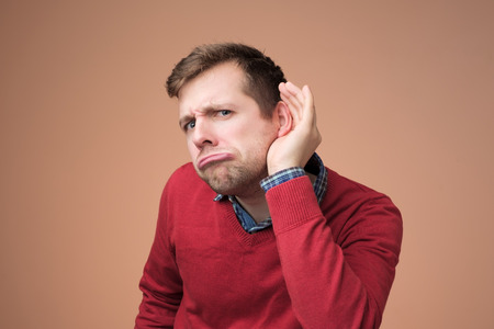 Man in red sweater trying to listen to latest gossip.の写真素材