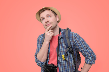 Tourist in hat with camera and backpack thinkingの写真素材