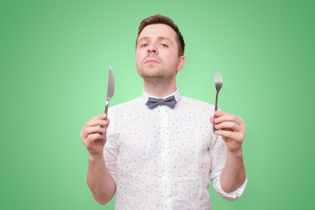 Hungry man holding fork and knife on hand to eatの写真素材