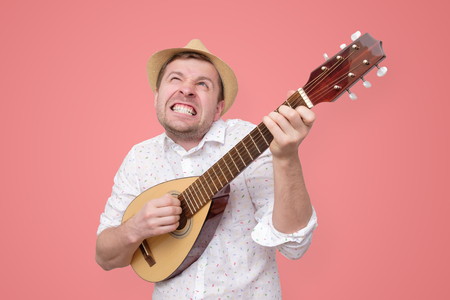 Man in summer hat playing guitar and singing songs.の写真素材