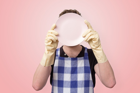 man in apron and rubber gloves holding clean plateの写真素材