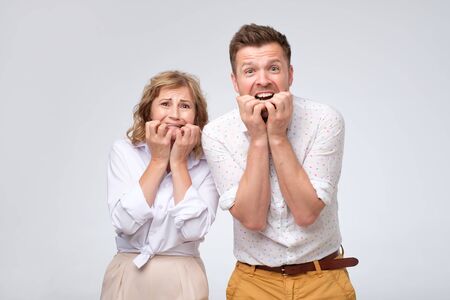 Scared man and woman biting their nails feeling stressed and surprised.の写真素材
