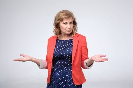 Pretty mature woman retired boss looking confused shrugs her shoulders.の写真素材