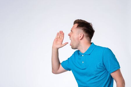 Handsome young man calling someone. Side view.