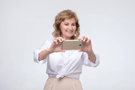 Senior woman makes a selfie in a studio