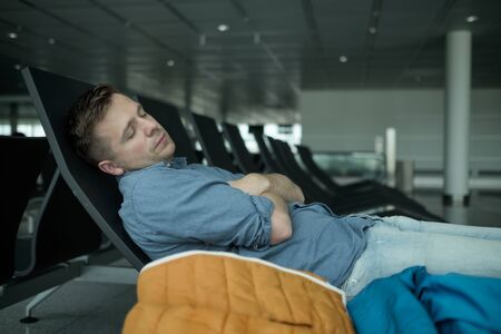 Mature man in airport sleeping on a benchの写真素材
