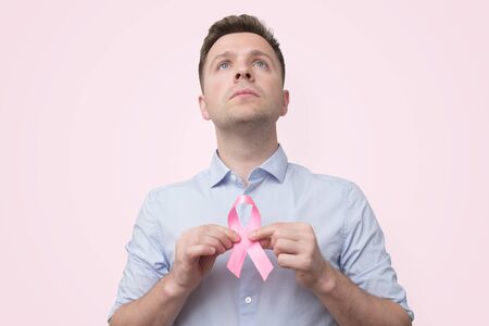 Saint-Petersburg, Russia - October 01 2019:Young caucasian man holding cancer ribbon. Studio shot.のeditorial素材