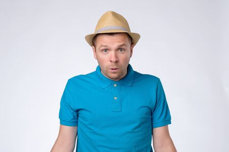 Confused handsome guy in summer hat and blue t-shirt.