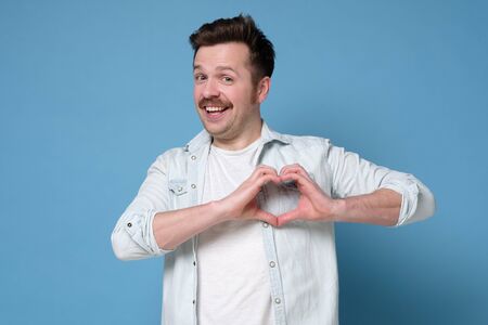 Smiling young boy making heart gesture on his chest. Valentine day concept.