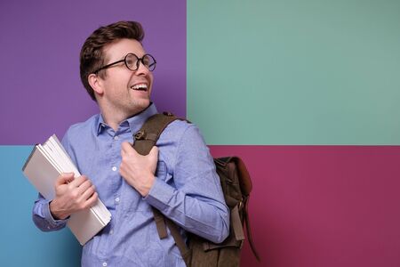 Confident student in glasses holding books looking aside on copyspace.の写真素材