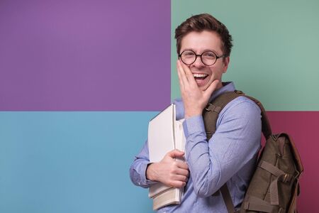 Confident student in glasses holding books looking aside on copyspace.の写真素材