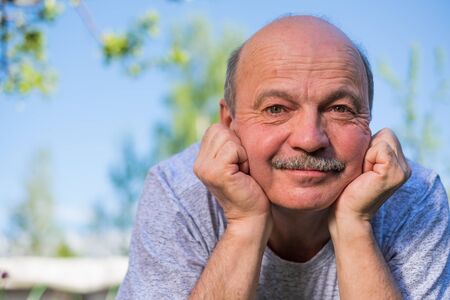 elderly spanish man resting, on fresh air lying on ground smiling at camera.の写真素材