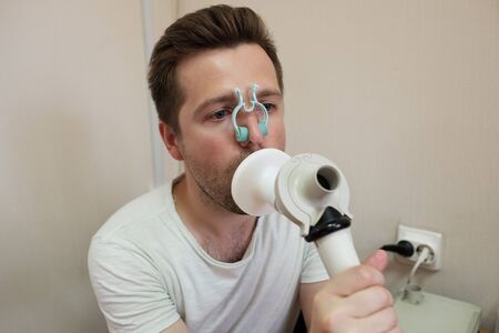 Young man testing breathing function by spirometryの写真素材