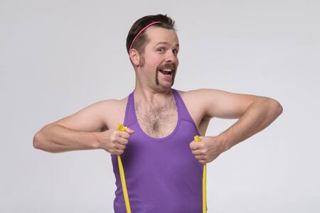 Young caucasian man exercising with rubber tapes isolated on grey wall.の写真素材
