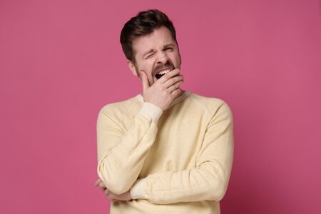 Funny caucasian man with mustache yawning having boring expression on pink wall. Studio shotの写真素材