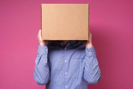 Anonymous business man with a cardboard box on his head concealing his identity. Studio shot
