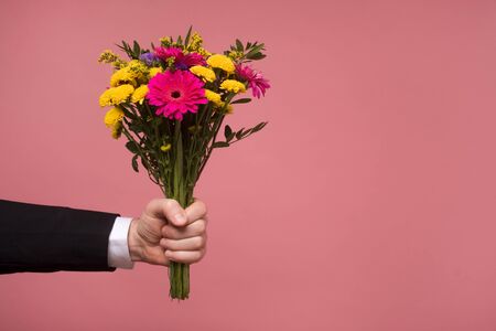 Male hands holding flowers isolated on the pink wallの写真素材