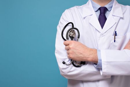 Caucasian medical intern or doctor with stethoscope and white clothes isolated on blue wallの写真素材