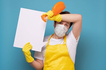Caucasian with spray bottle of anti bacterial liquid soap for cleaning home and copyspace. Disinfection and hygiene concept. Isolated on blue background.の写真素材