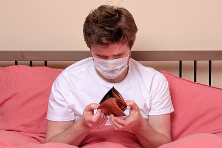 Unemployed sad man in medical mask and suit showing empty wallet