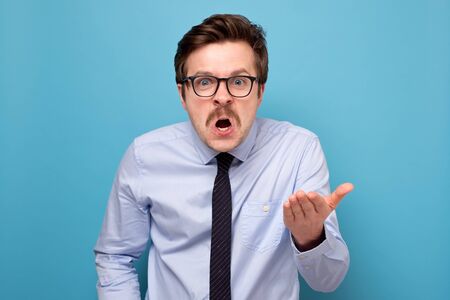 Portrait of a angry young man pointing finger at you camera gesture isolated on gray wall backgroundの写真素材