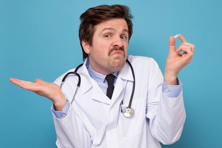 doctor man holding prescription pills thinking about questionの写真素材