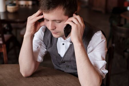 Man having a hard conversation on phone trying to stay calmの写真素材