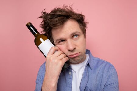 Sad caucasian man complaining and drinking wine alone. Studio shot