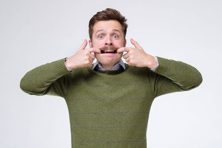 Young caucasian man stretching out his cheeks. Studio shotの写真素材
