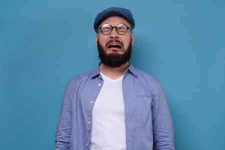 Sad caucasian man in blue cap and glasses crying.の写真素材